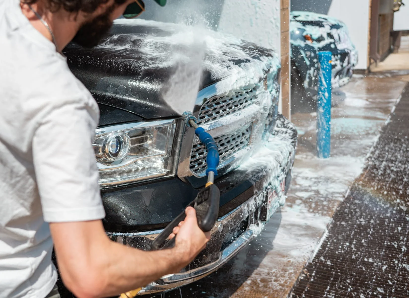 Customer using a foam brush to clean a vehicle at a self-service wash bay