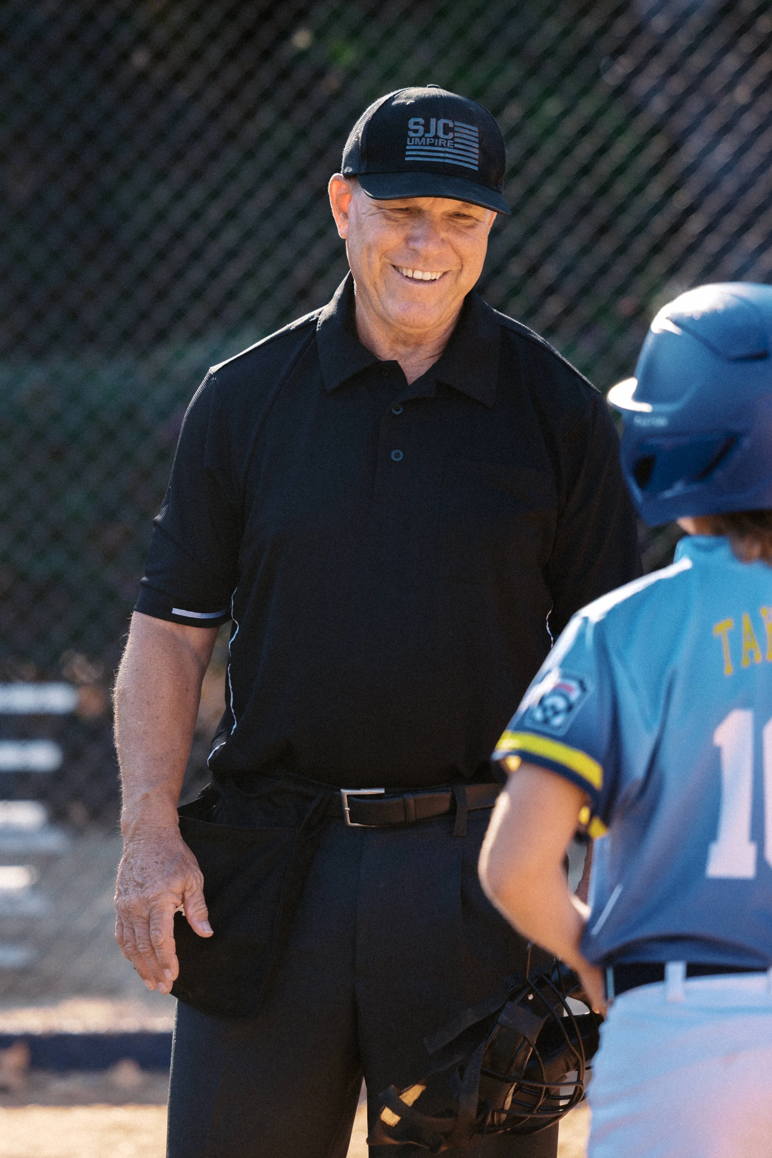 Jeff in his 'SJC UMPIRE' uniform chatting with a baseball player