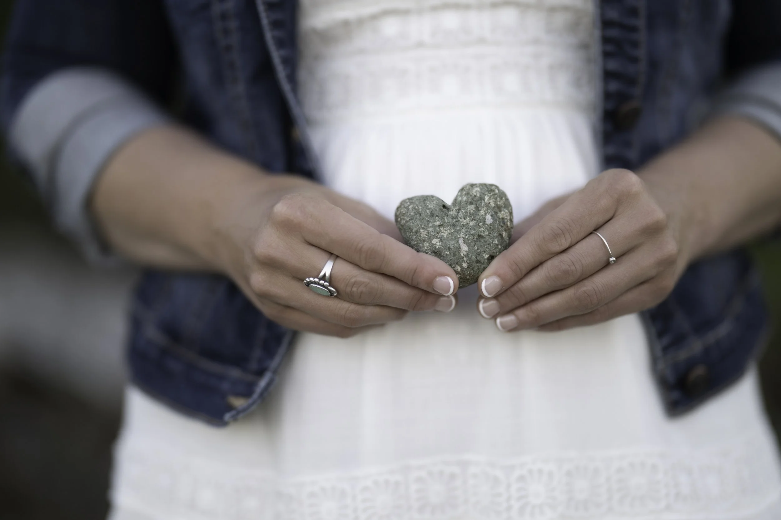 Person holding a heart-shaped rock with both hands.