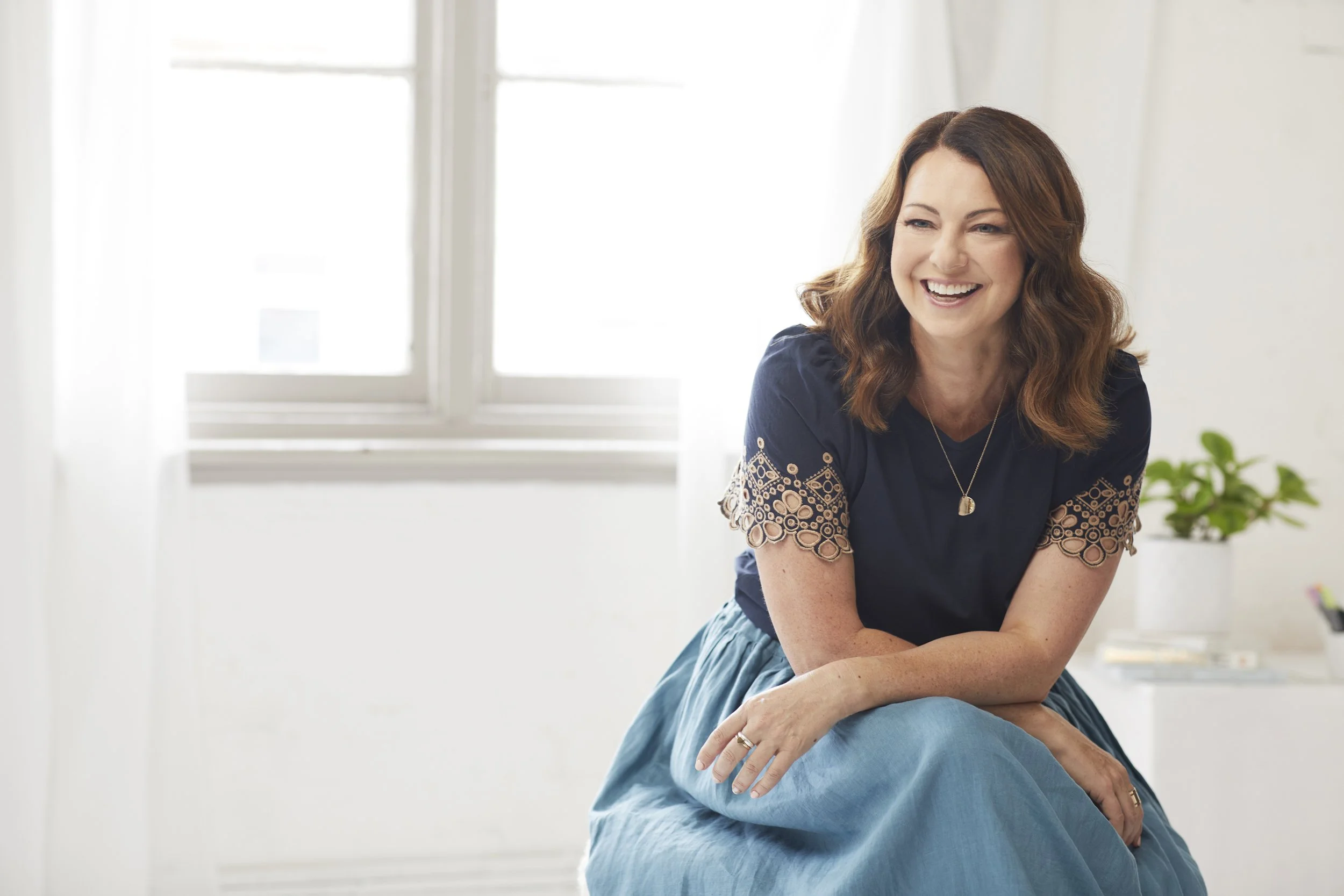 Woman smiling, sitting indoors