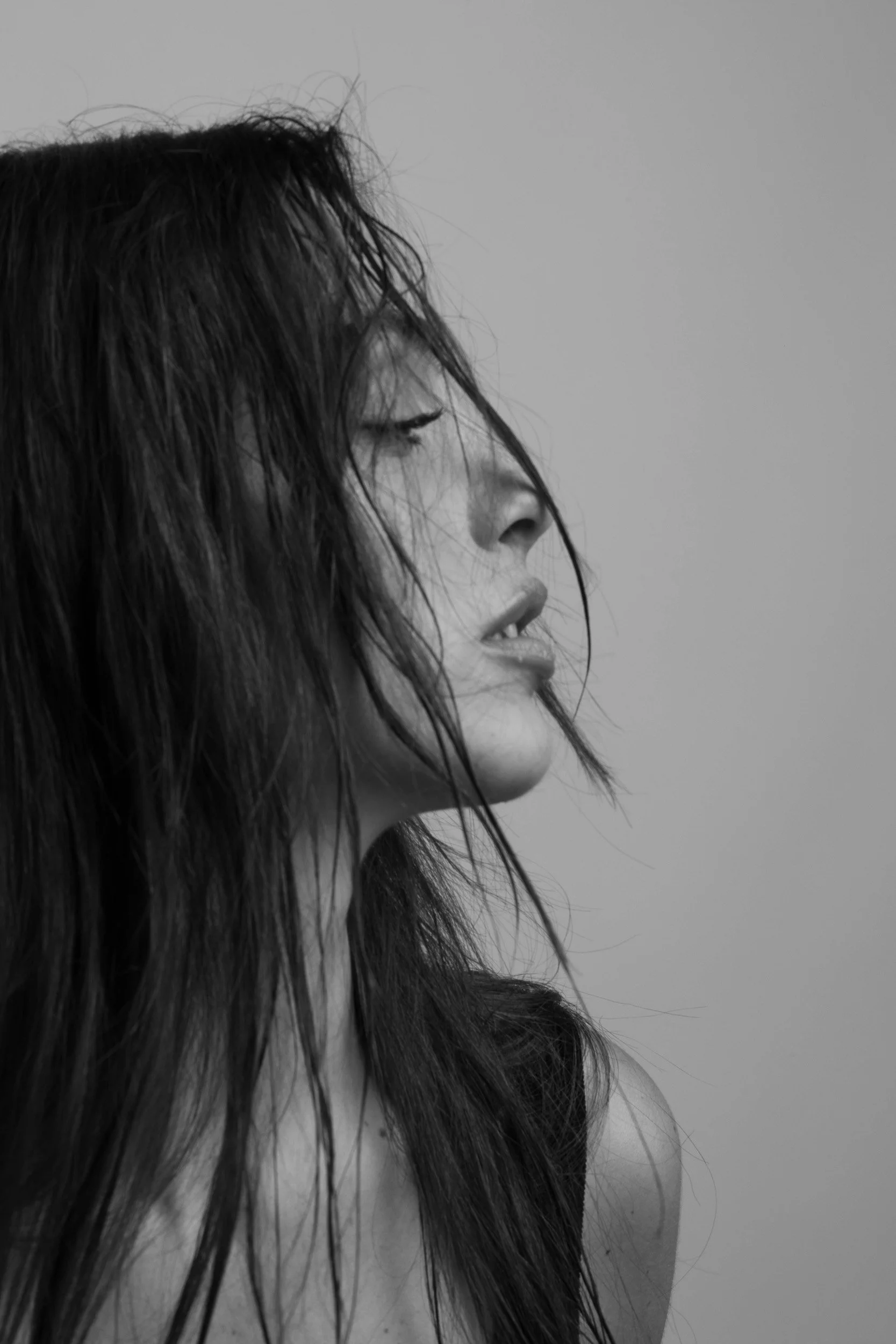 Profile view of a woman with wet hair, eyes closed, grayscale photo