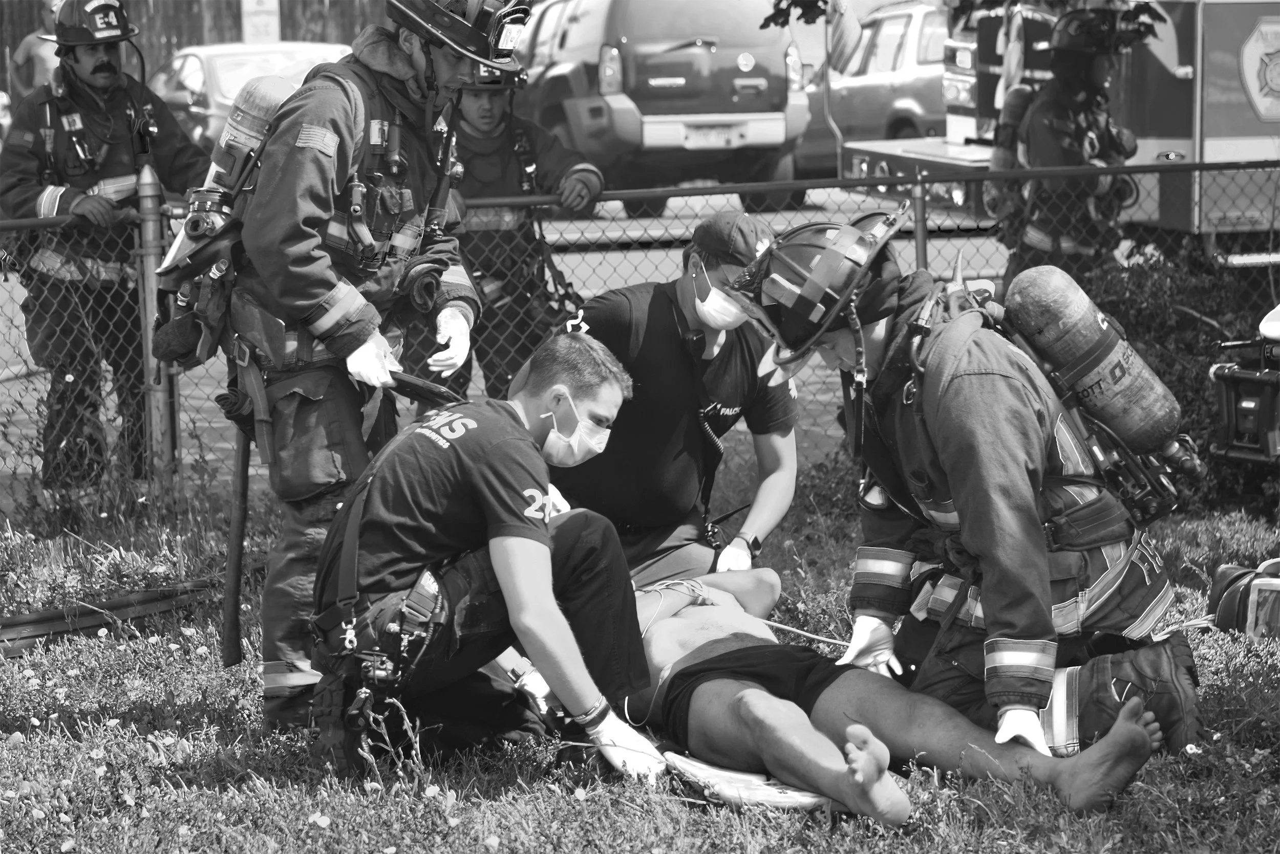 Firefighters attending to an individual lying on the ground during an emergency situation.