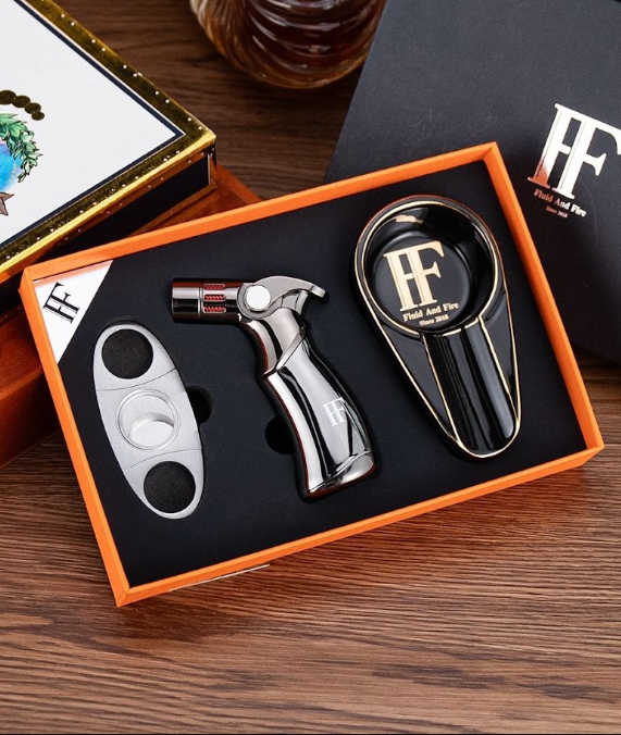 A black and silver cigar cutter set with a cigar cutter and an ashtray in an orange box on a wooden surface.  Sold at Outlaw Vapor in Preston and Malad, Idaho.