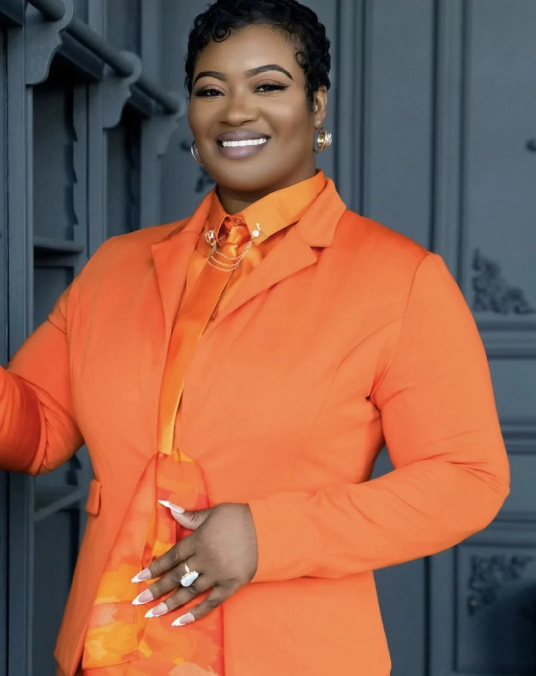 Meet Keisha, founder and lead stylist of LuxoriGLAM Hair Emporium, a Toronto luxury pixie hair specialist, wearing an orange suit.