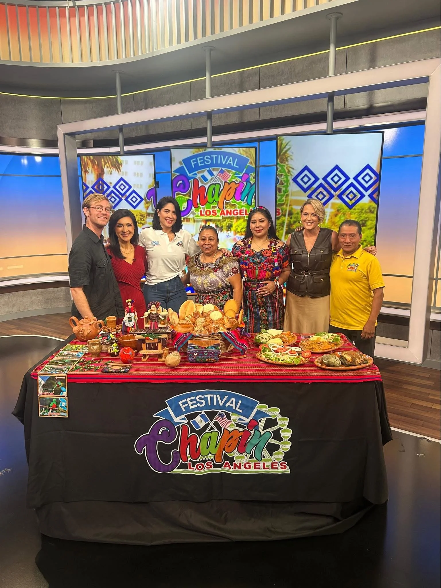 Group of people standing behind a table filled with traditional Mexican foods at the Festival of Ch condom in Los Angeles.