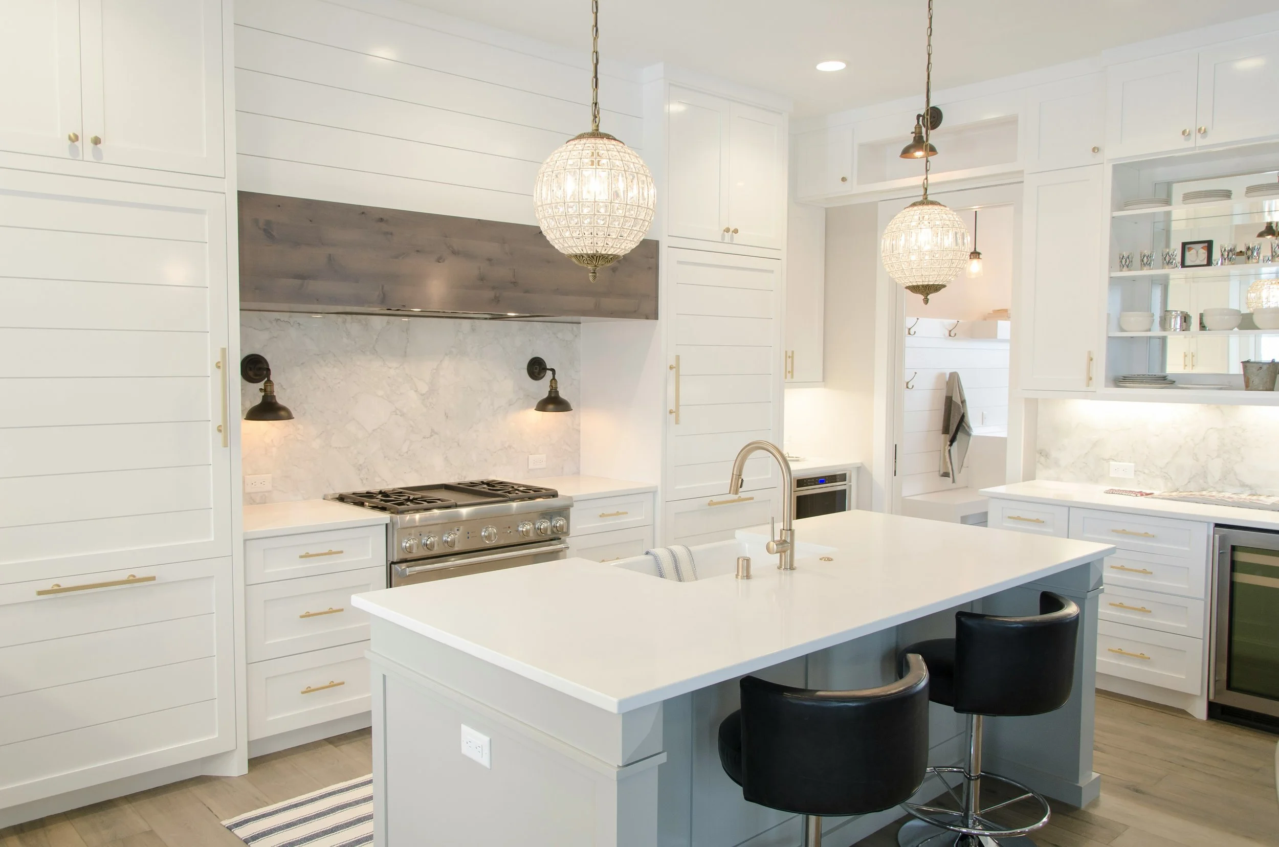 Modern white kitchen with a kitchen island, pendant lights, and built-in shelving.