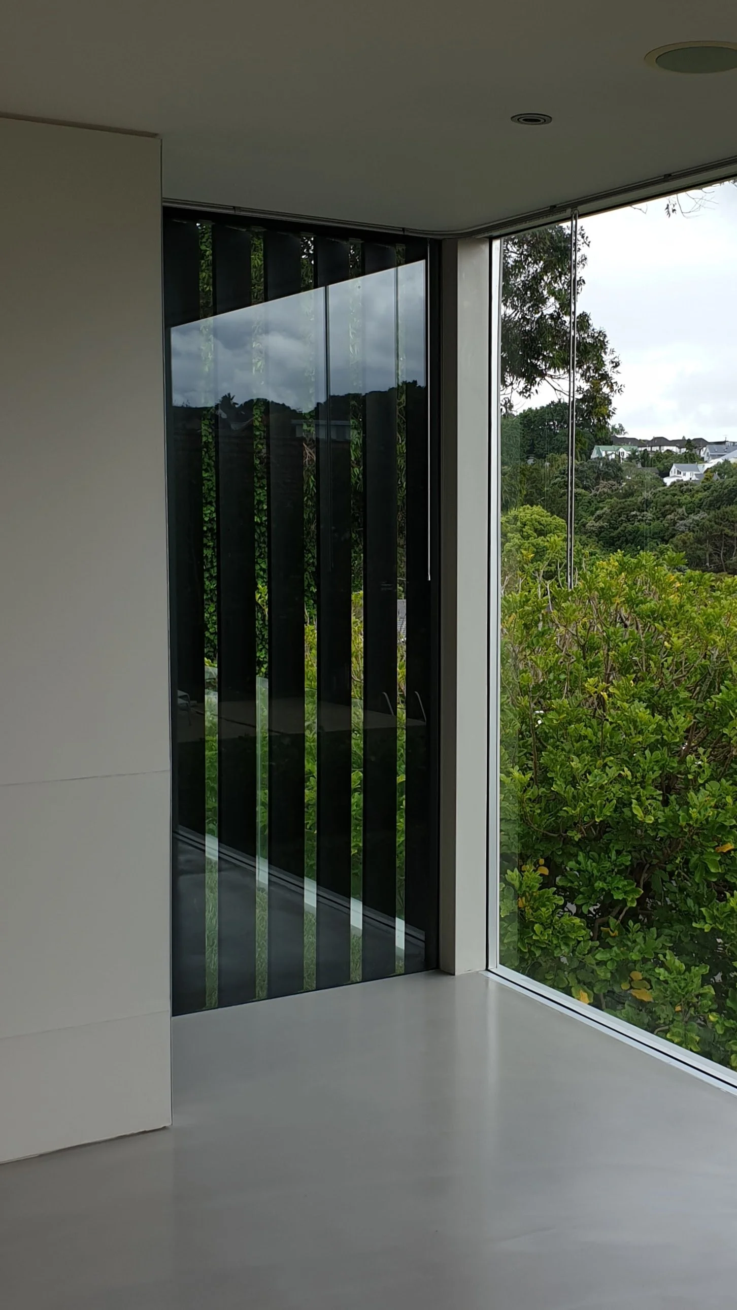 Modern interior with floor-to-ceiling window showing trees and greenery outside