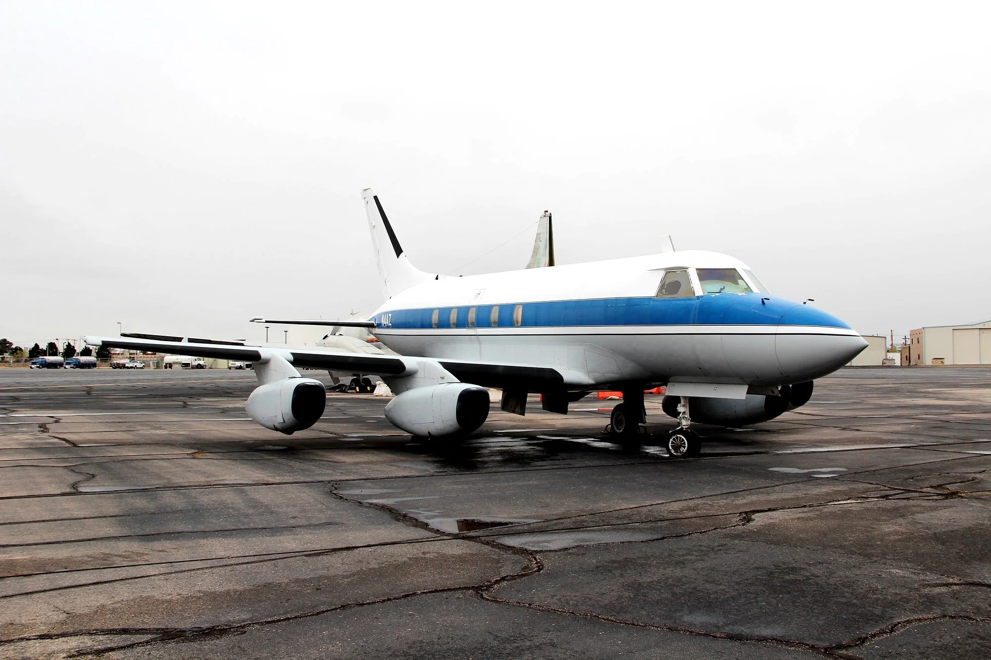 A white and blue commercial airplane parked on an airport tarmac.