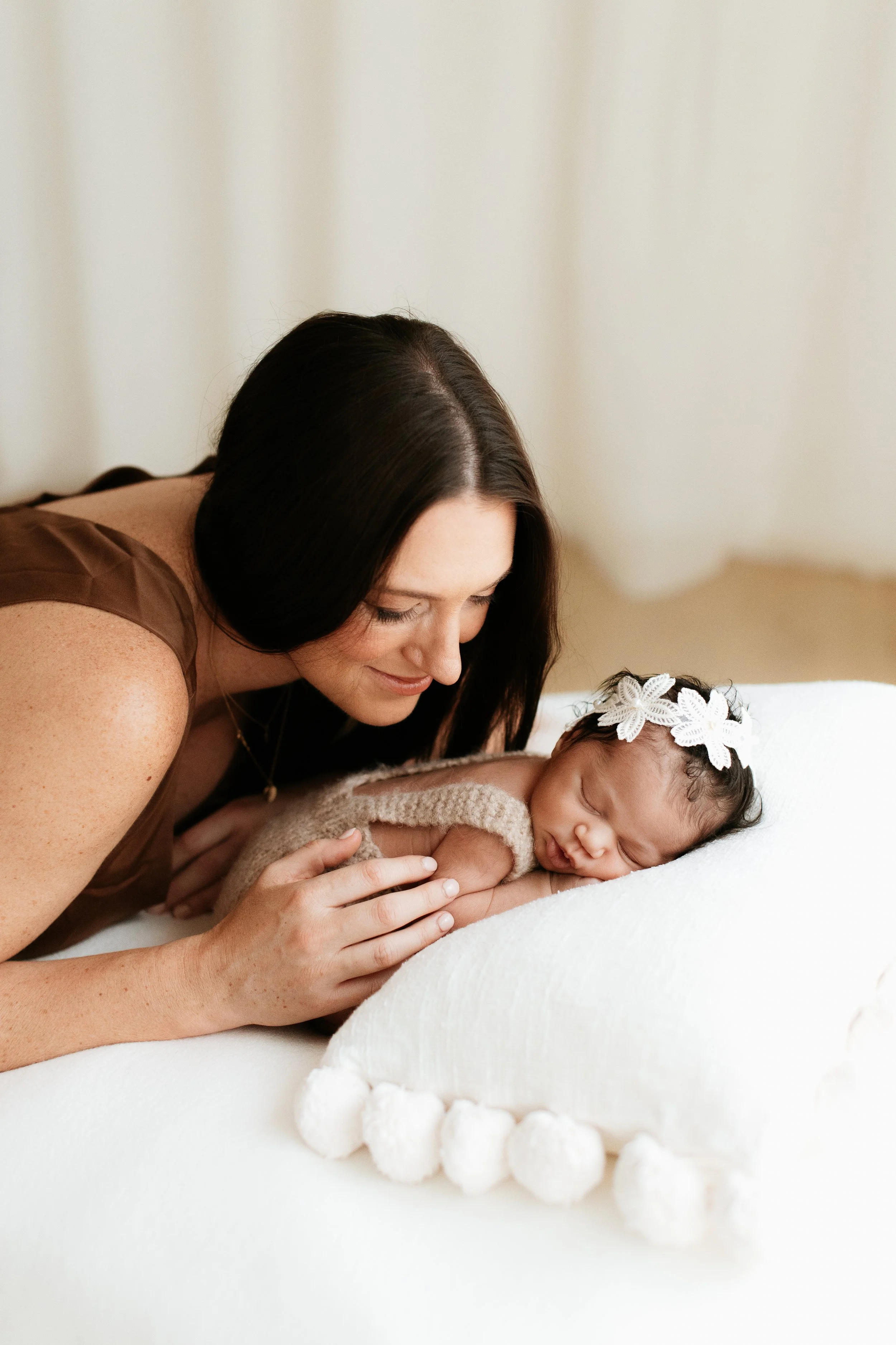 Luxury newborn photography in Melbourne capturing a mother admiring her sleeping newborn baby in soft natural light.