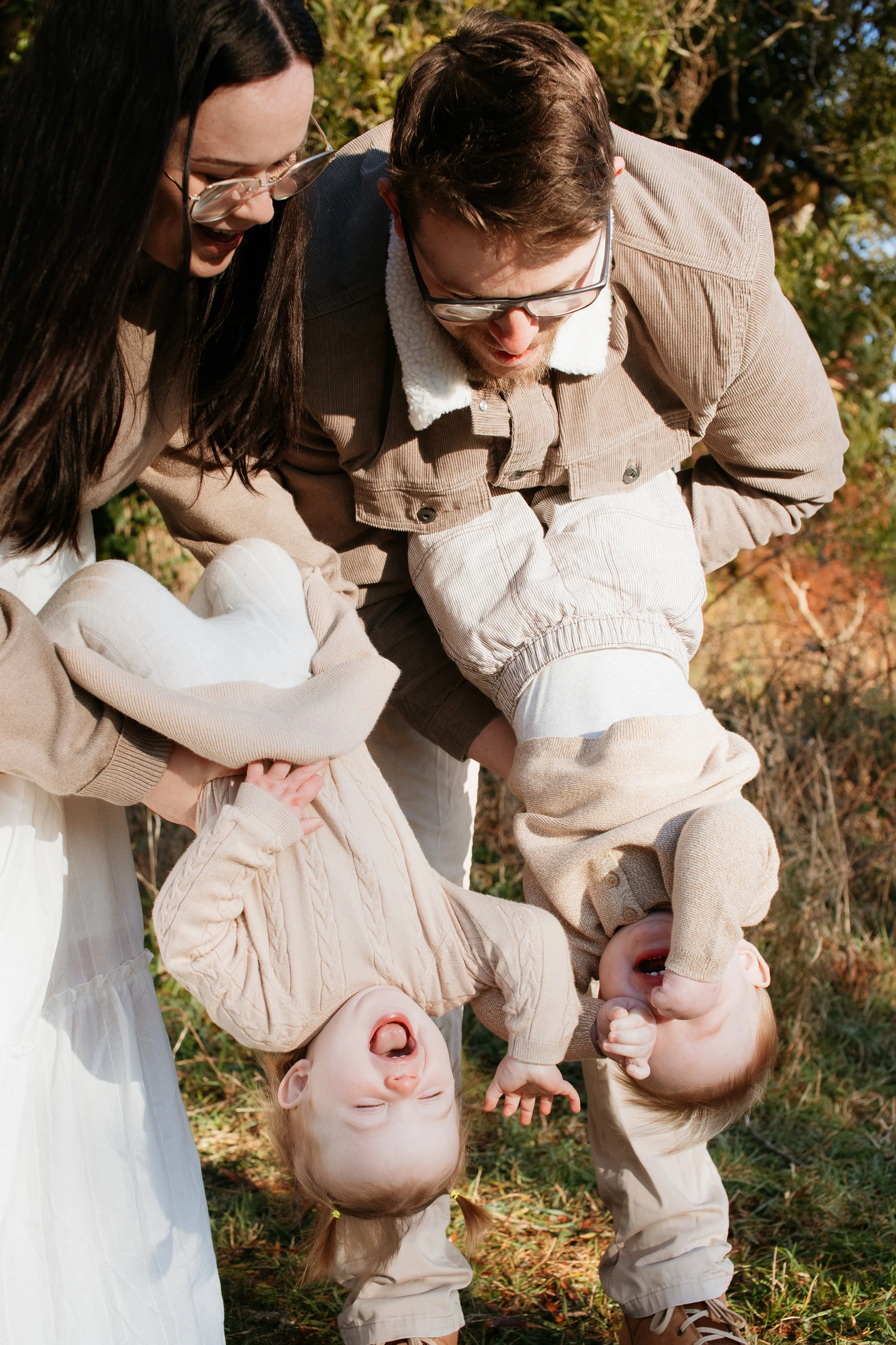 Outdoor family photography in Melbourne featuring parents playing with their young children in a fun, candid portrait.