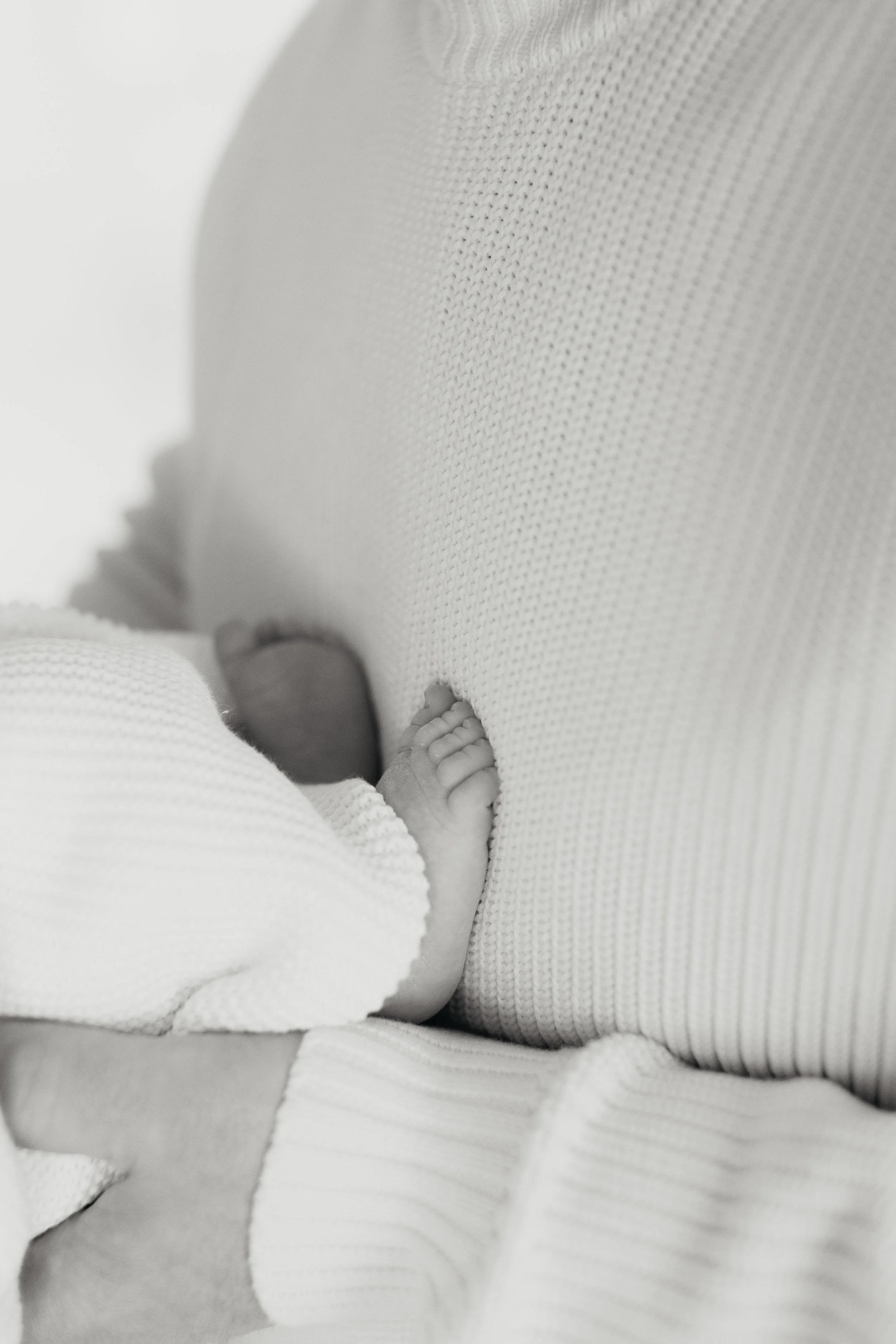 Close-up of a newborn baby's foot resting on a soft, textured, white blanket.