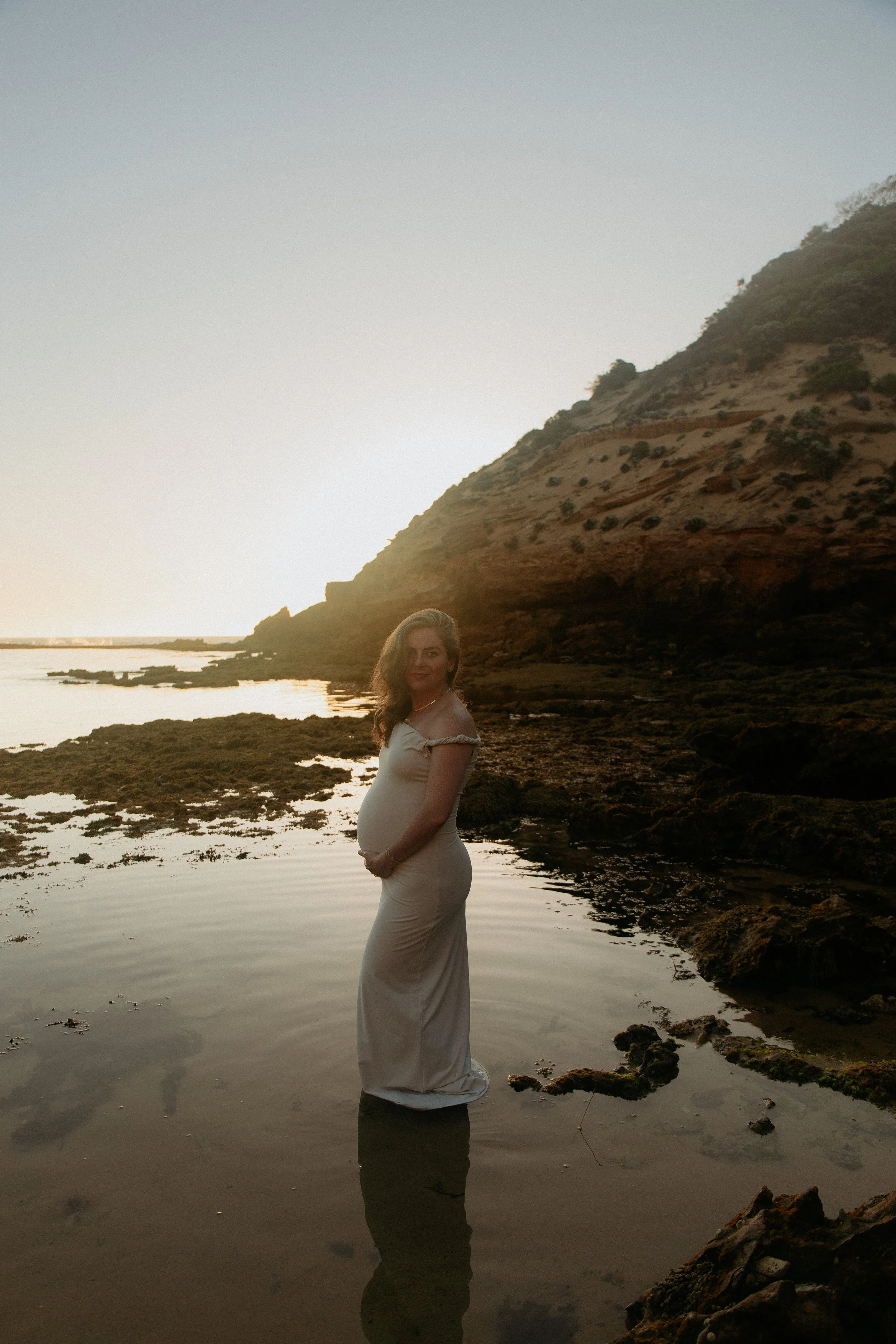 Bump to Baby photography in Melbourne featuring an expectant mother standing on the beach during a golden hour maternity session.