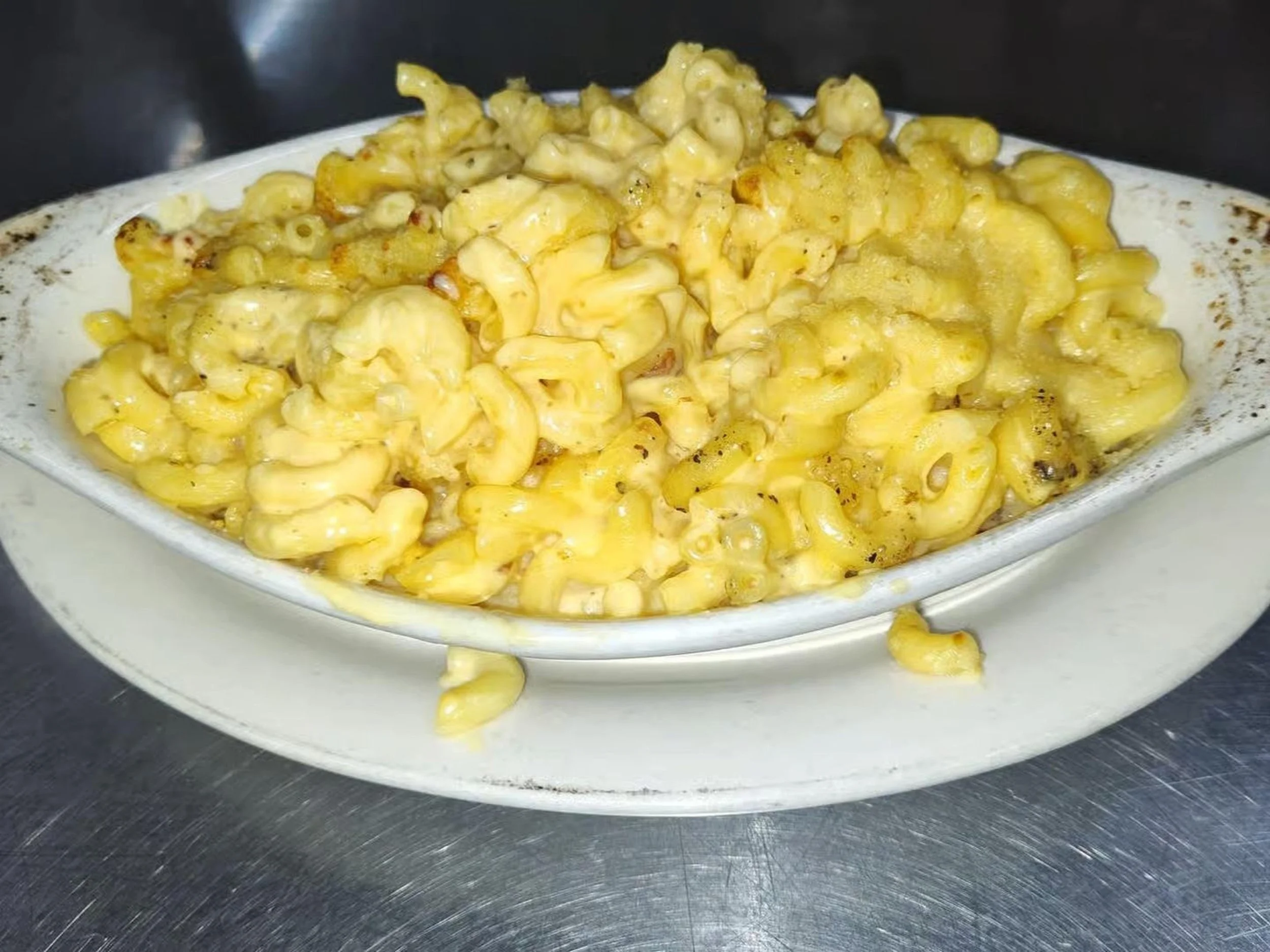 Baked macaroni and cheese in a white casserole dish on a stainless steel surface.