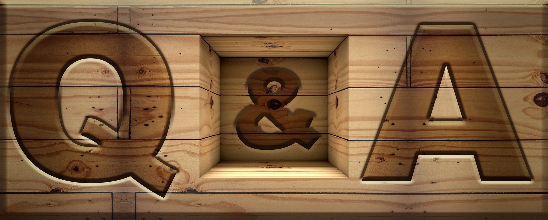 Wooden sign spelling out 'Q&A' with large cutout letters on a wood plank background.