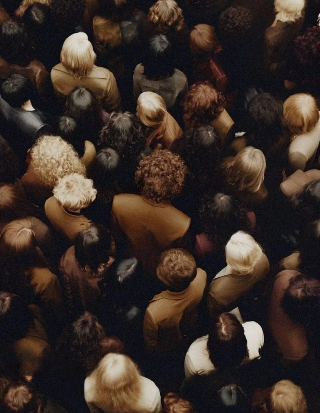 Crowd of people viewed from above, wearing various colored clothing, gathered in close proximity.