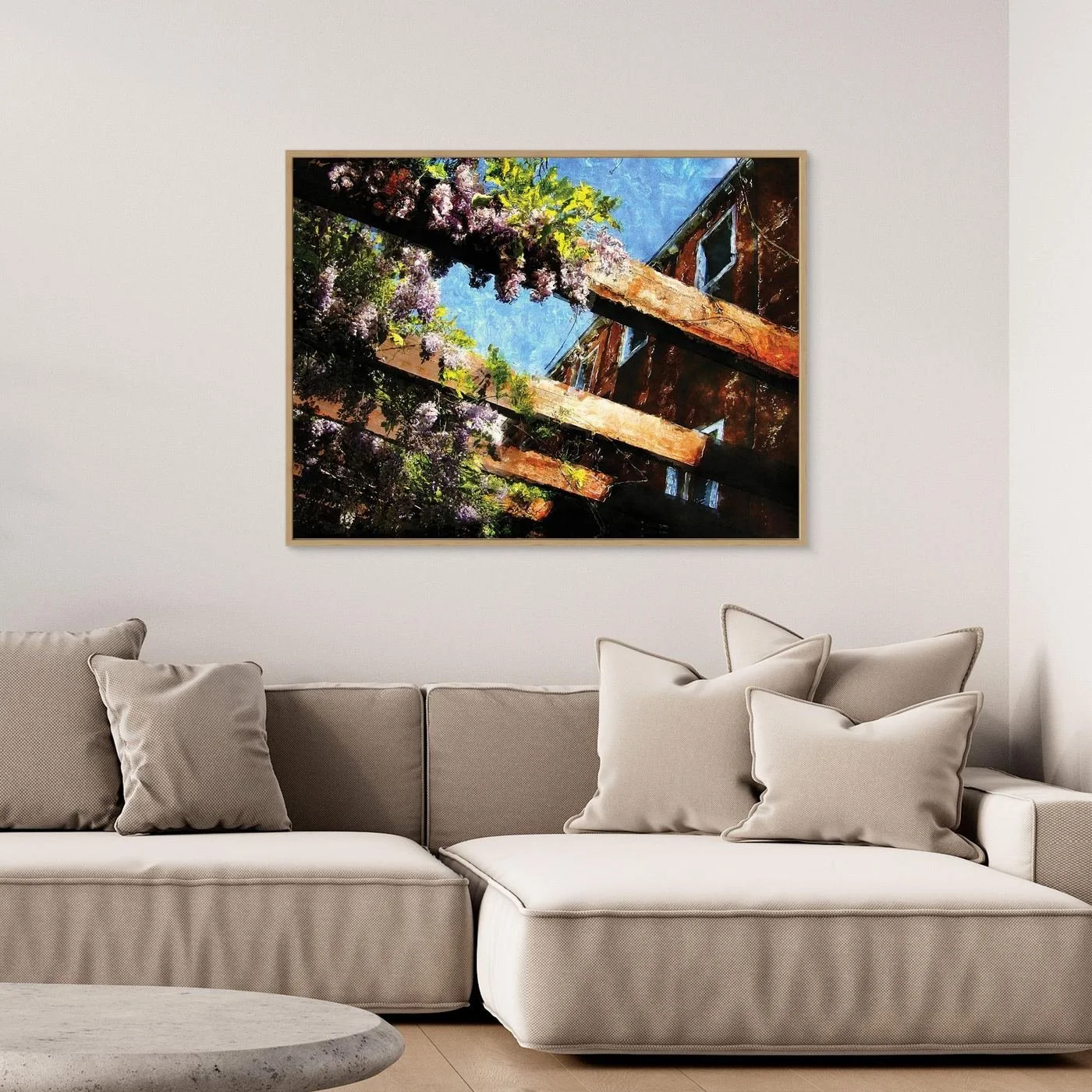 Impressionist fine art print showcasing purple wisteria flowers climbing over rustic wooden pergola beams against a textured blue sky, framed and ready to hang. Over grey couch