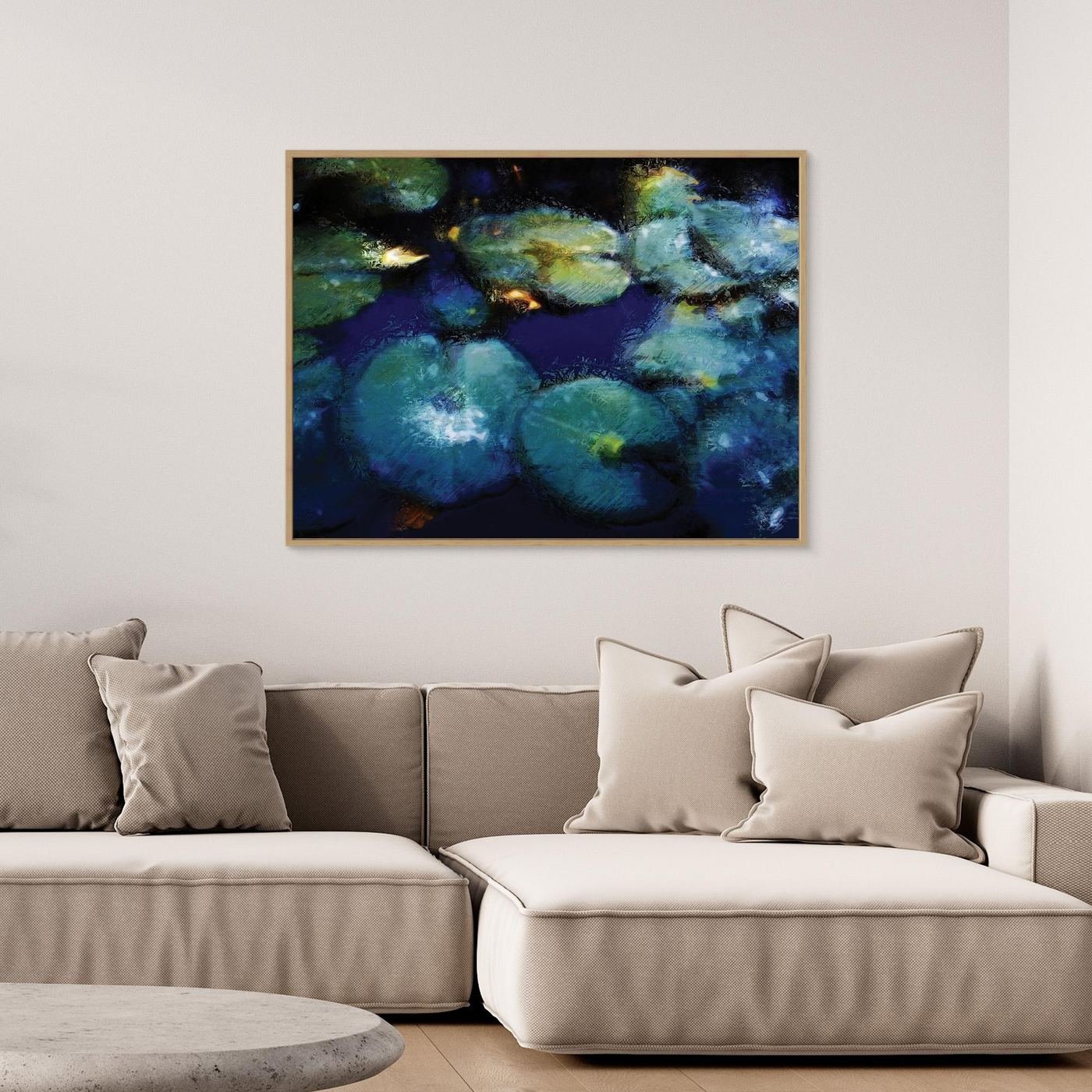 Abstract fine art print evoking a serene pond with lily pads in deep blue, teal, and green tones with impressionistic light textures, framed and ready to hang. Over grey couch