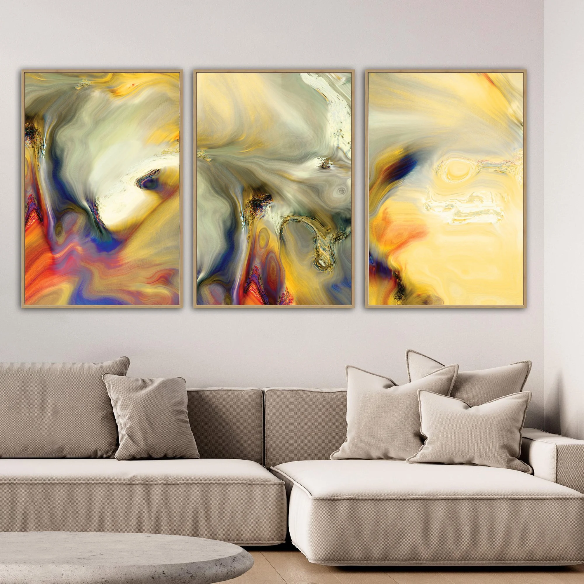 Abstract triptych with liquid textures in warm gold, ocher, and cream, contrasting with deep navy blue and terracotta swirls, framed and ready to hang. Over grey couch