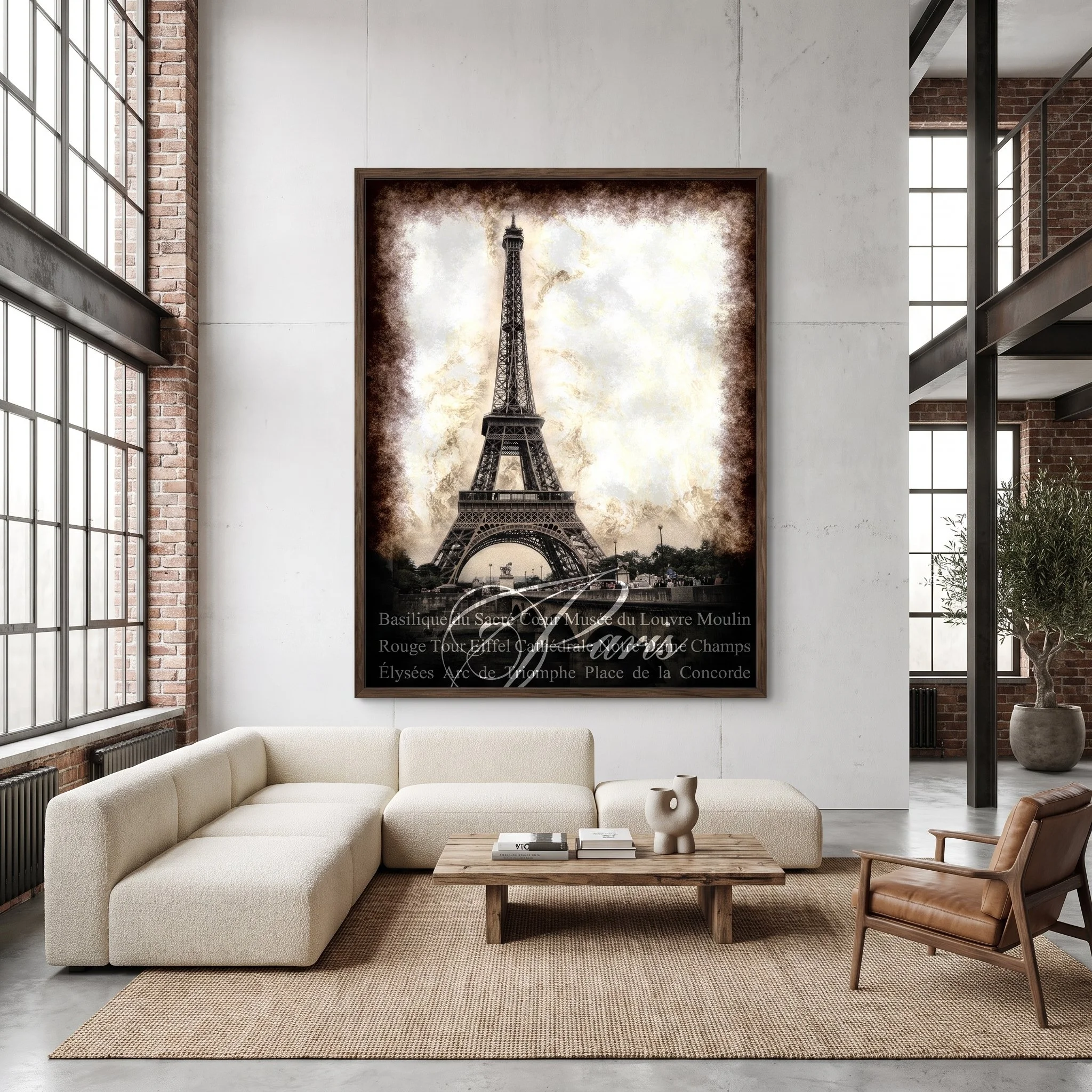 Large art fine art print of the Eiffel Tower hanging on a white wall in a bright industrial loft with a cream sectional sofa, exposed brick, and large windows