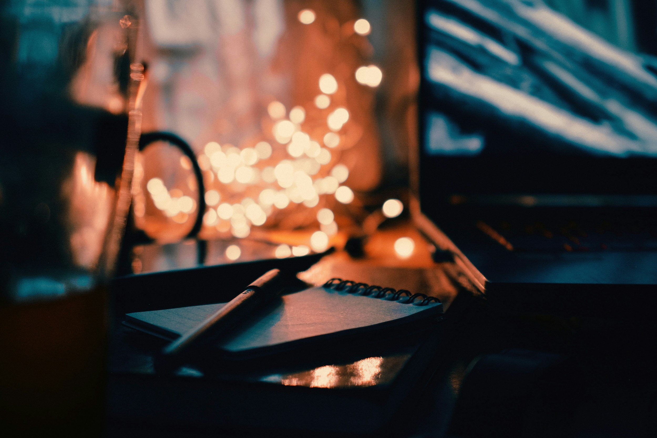 Close-up of sparks and flames from a welding or metalworking process, with a notebook and pen on a dark work surface in the foreground.