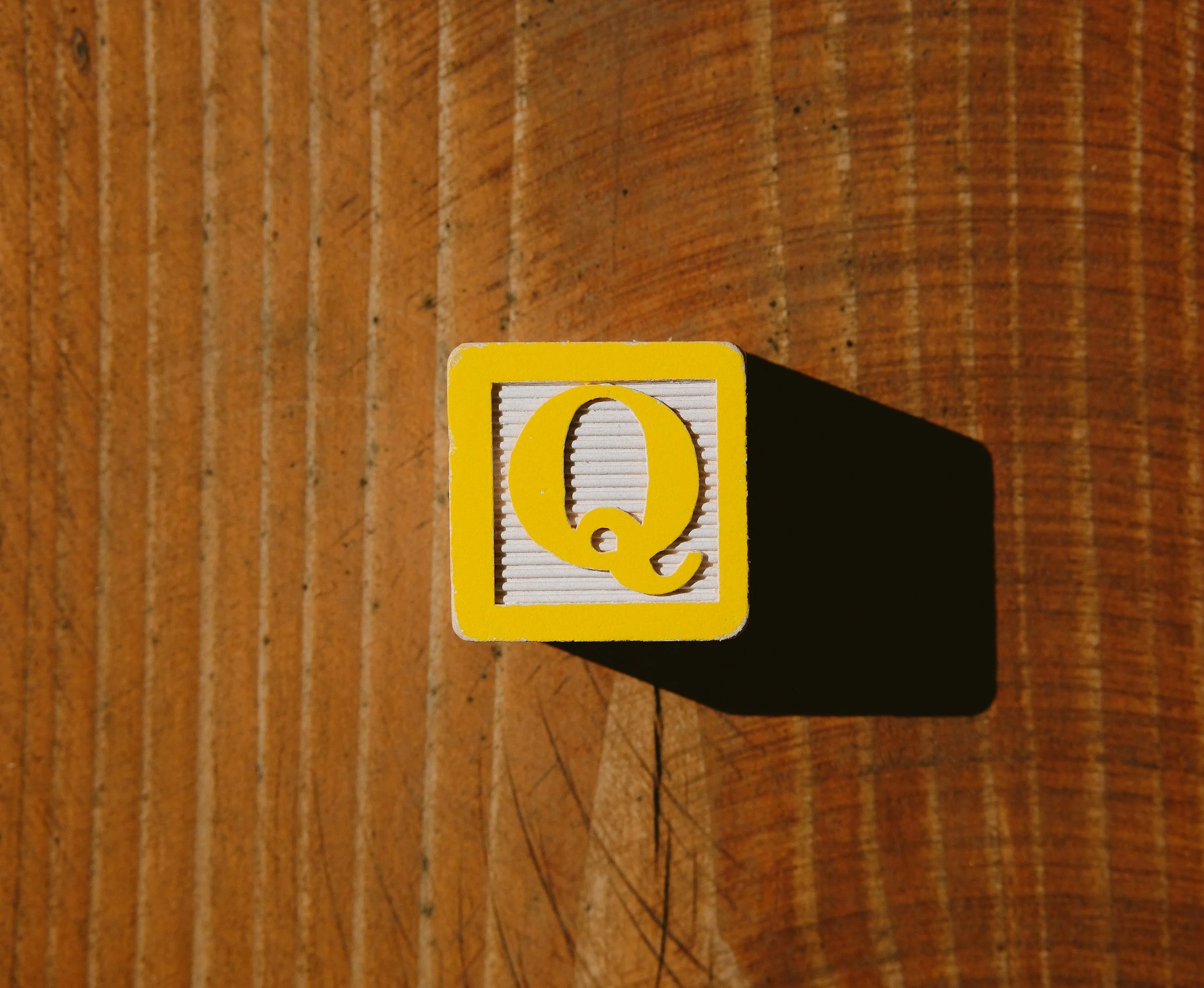 Close-up of a yellow photo card with a white ribbed section and a yellow '@' symbol on it, placed on a wooden surface.