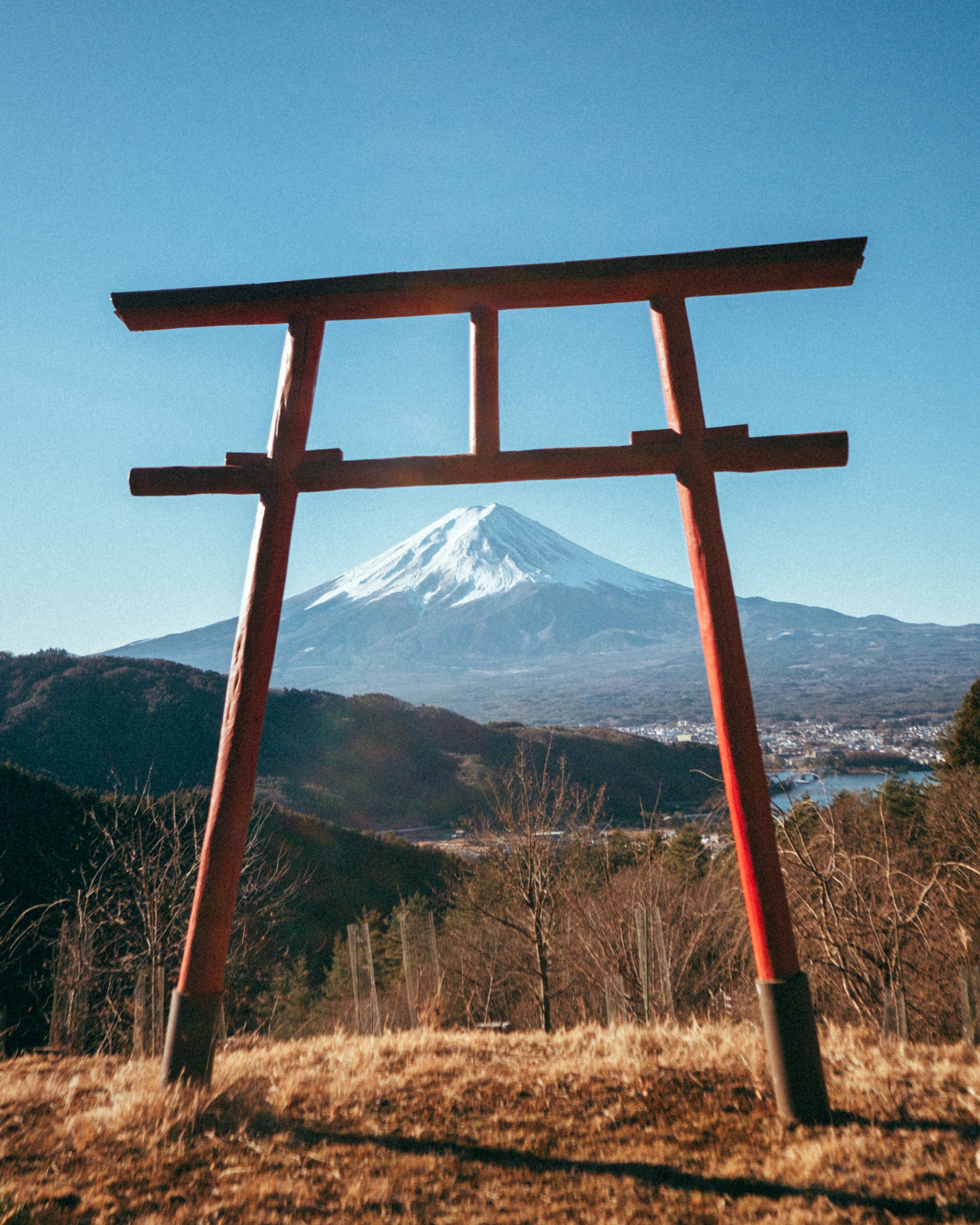 A red torii gate with Mount Fuji snow-capped in the background, under a clear blue sky.