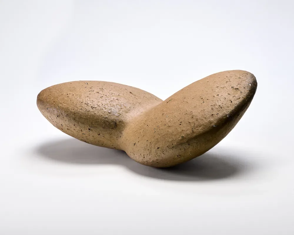 A smooth, oval-shaped stone with a light brown color, set against a plain white background.