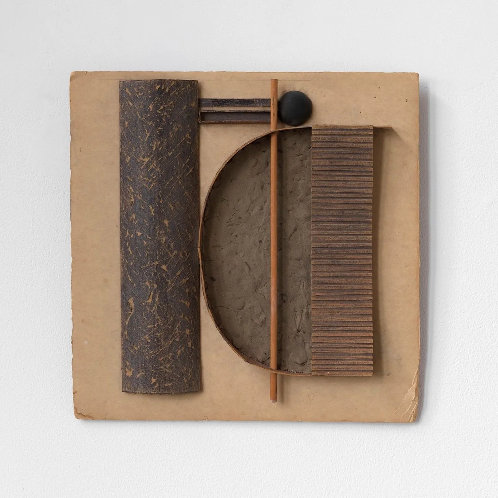 Mixed media art piece with geometric shapes and textured surfaces mounted on a wooden board.