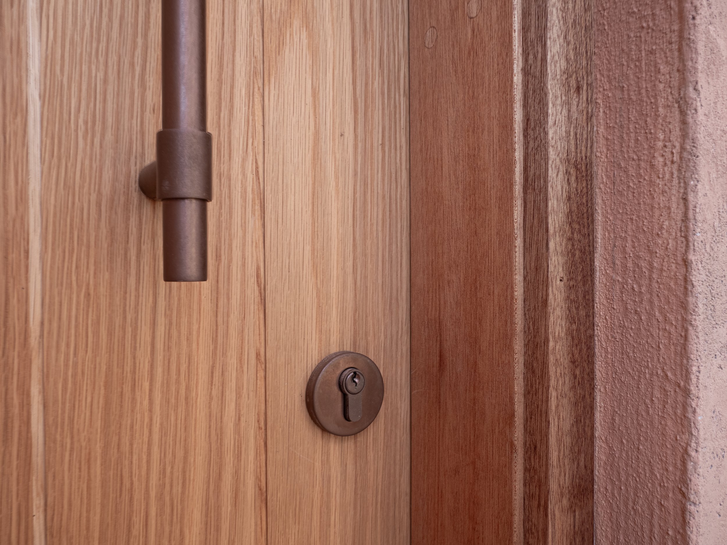 Close-up of a wooden door with a metal latch, deadbolt, and lock.