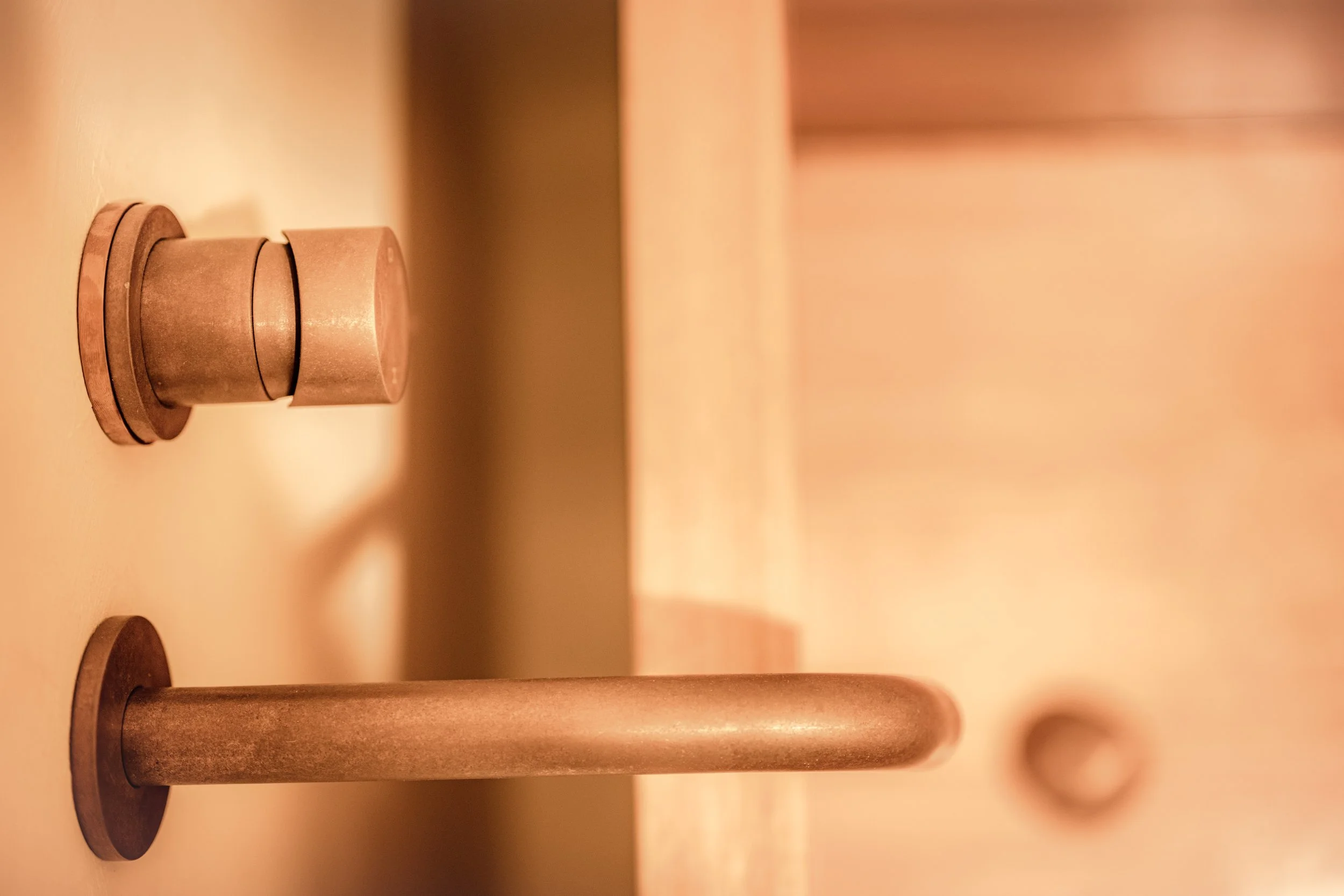 Antique bronze hardware set against a lime-washed wall.