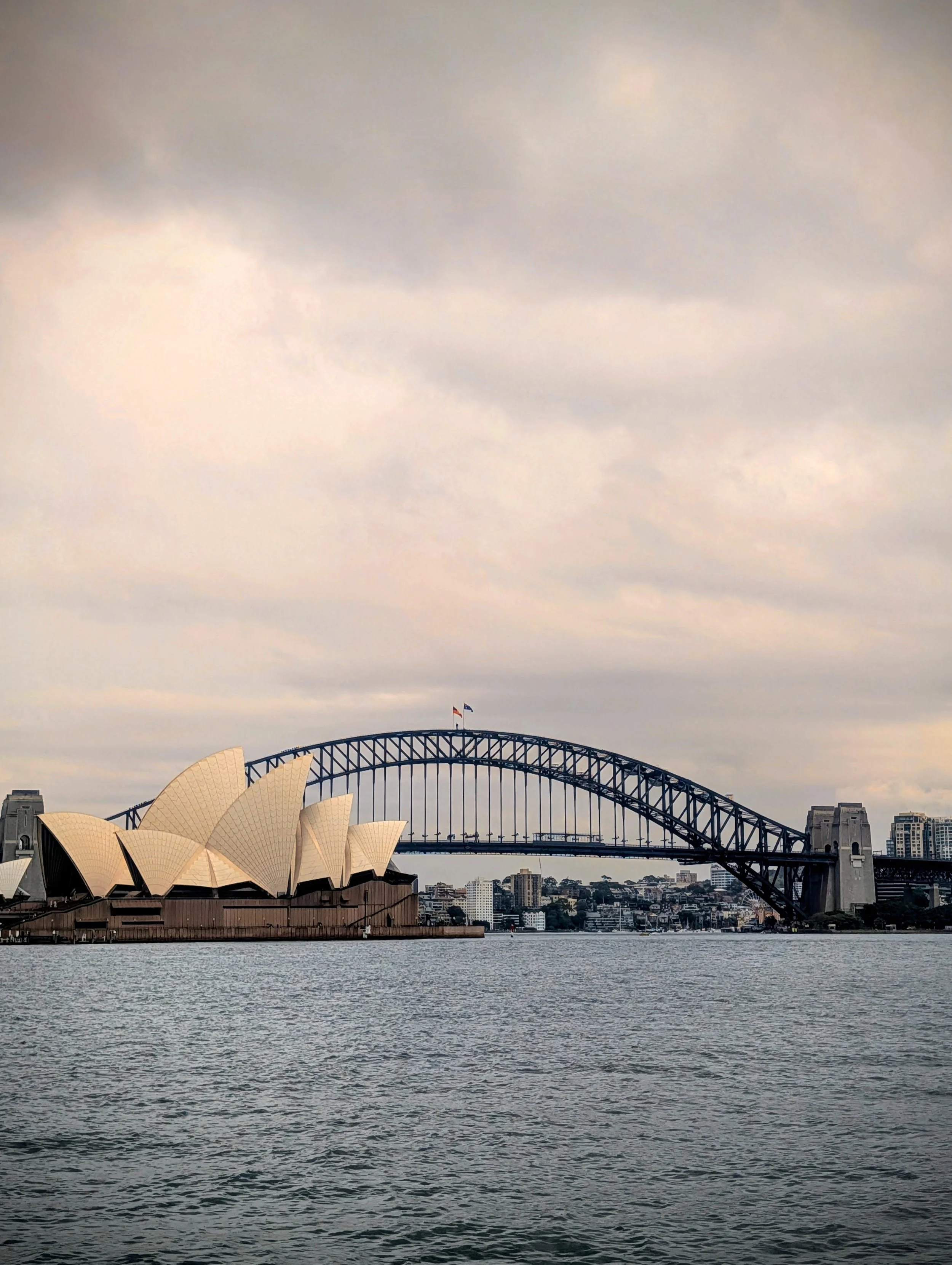 Sydney Opera House and Sydney Harbour Bridge with city skyline in the background under a cloudy sky