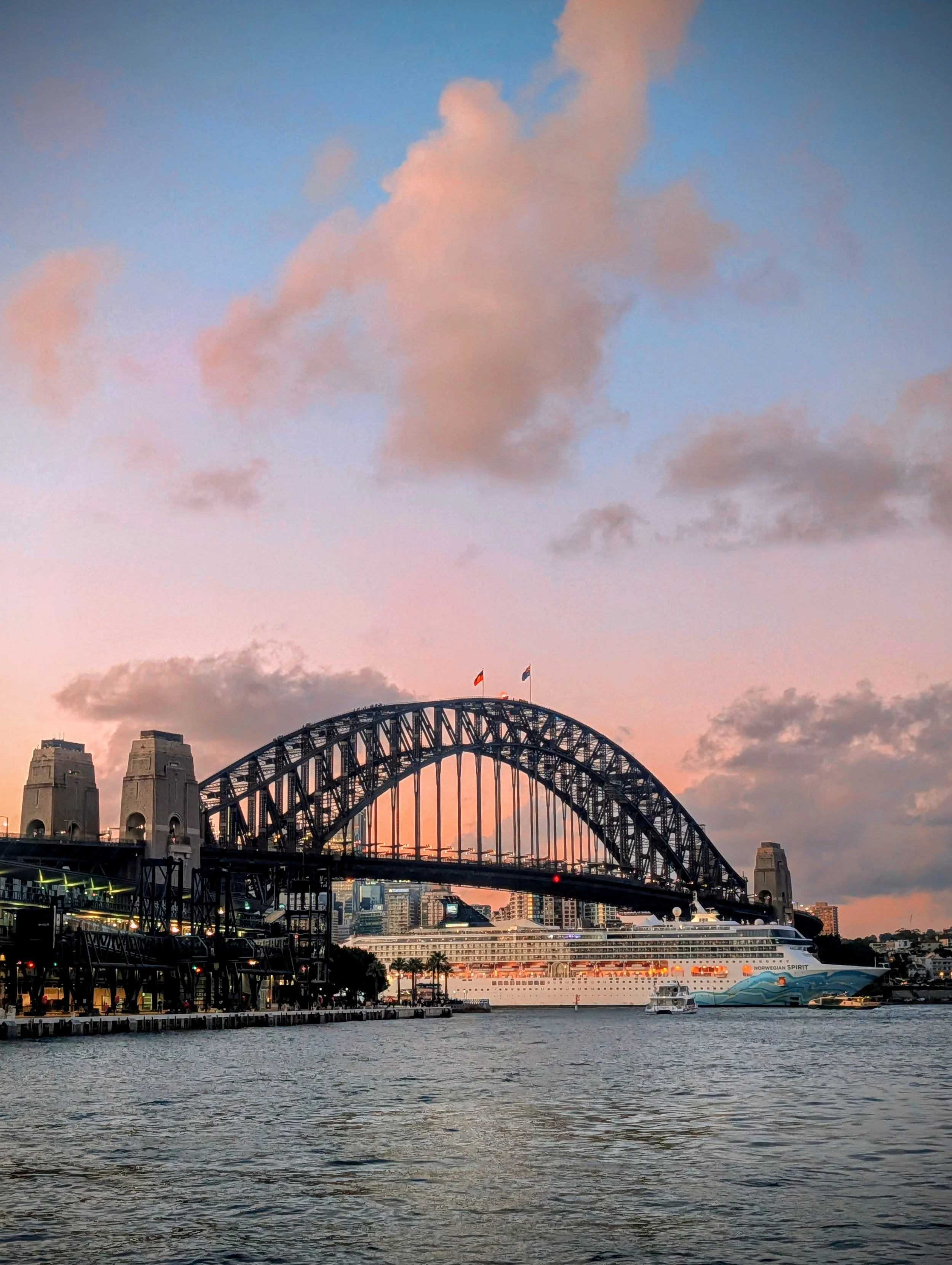 Sydney Harbour Bridge at sunset with a ferry and a cruise ship on the water