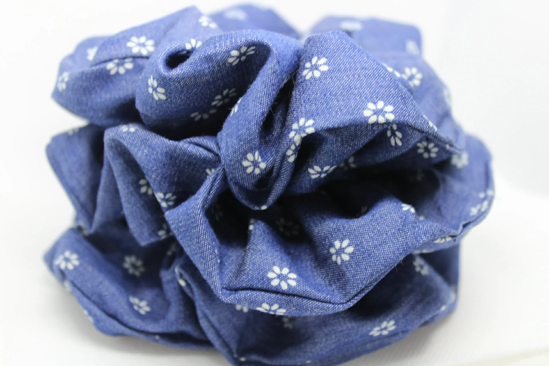 Blue fabric scrunchie with small white floral patterns.