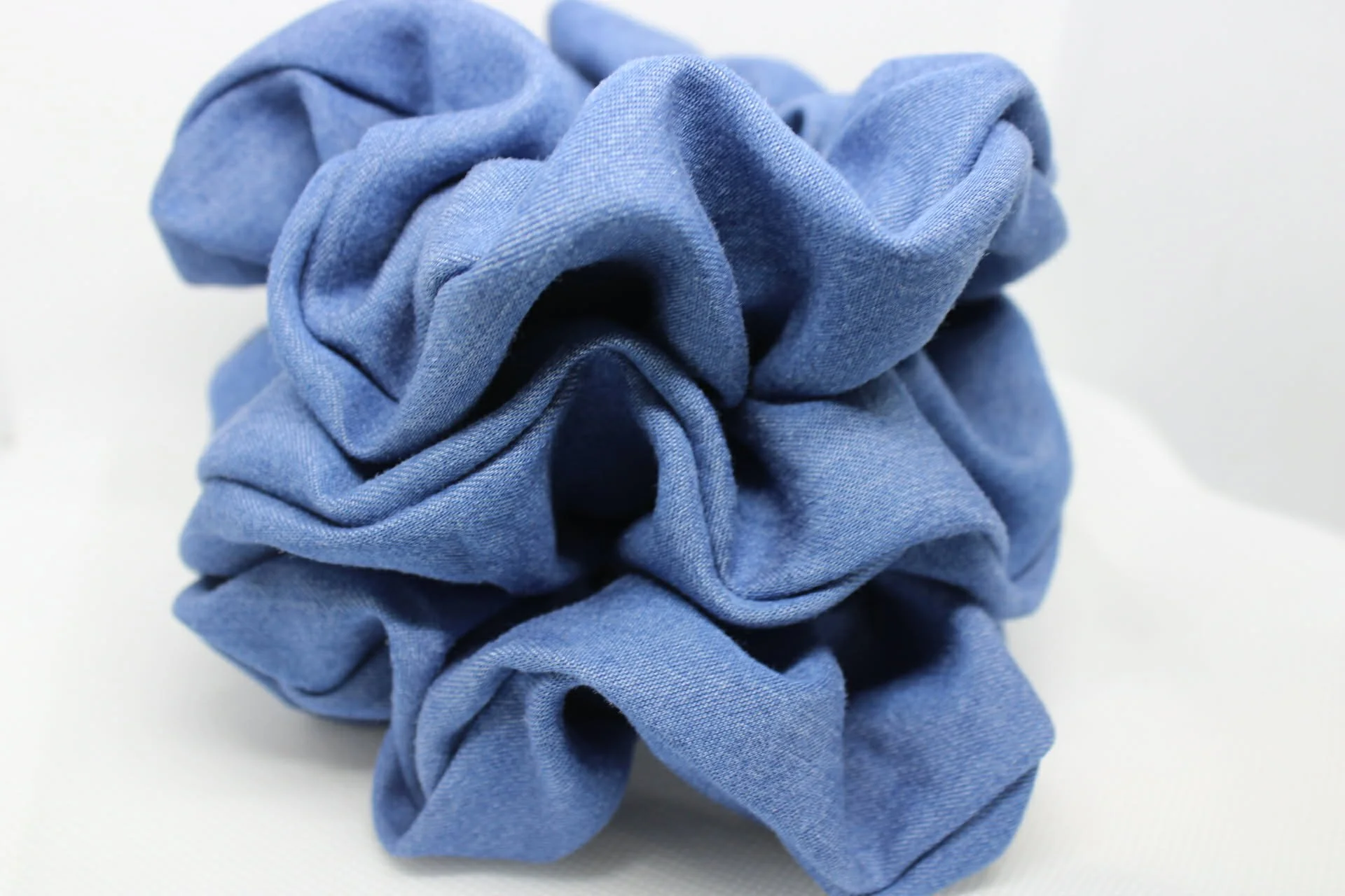 A light blue fabric scrunchie on a white surface.