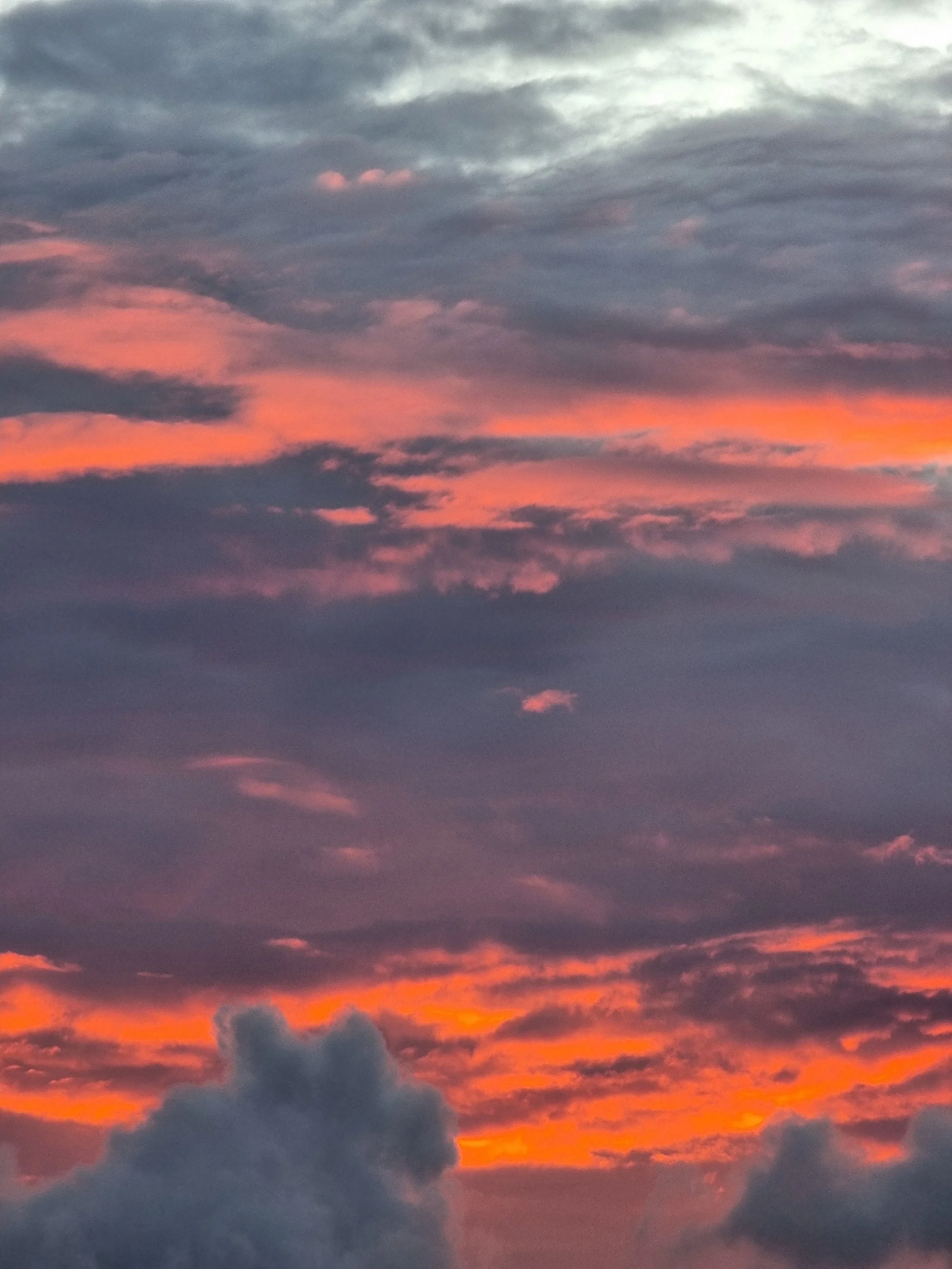 A colorful sky at sunset with clouds glowing in shades of pink, orange, and purple.