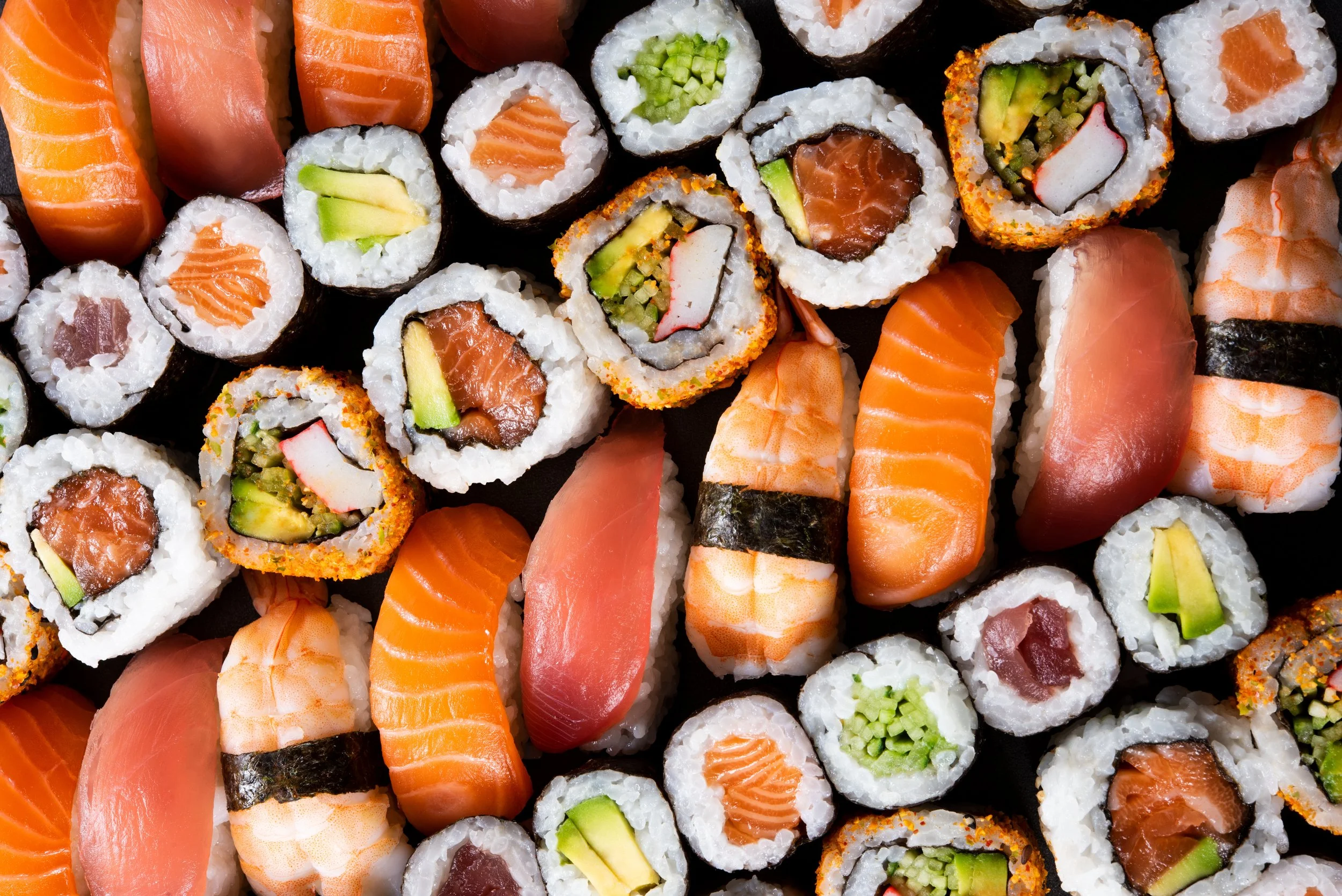 Assorted sushi rolls and nigiri featuring salmon, tuna, avocado, cucumber, crab, and shrimp.