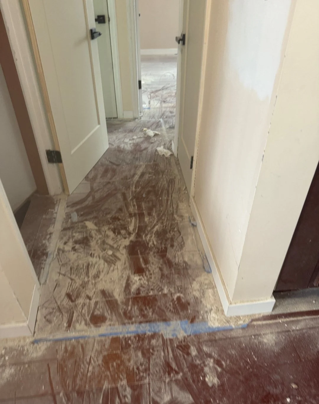 A hallway with dirt and debris on the tile floor, suggesting recent renovation or cleanup work.