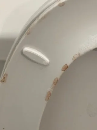Close-up of a white surface with a small lever and some rust spots.