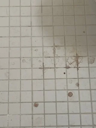 Dirty tiled floor with some stains and spots.
