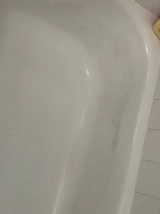 Inside a bathtub with slight dirt or stain marks.