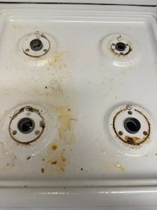 Dirty stovetop with four burners, some burnt-on residue, and rust.