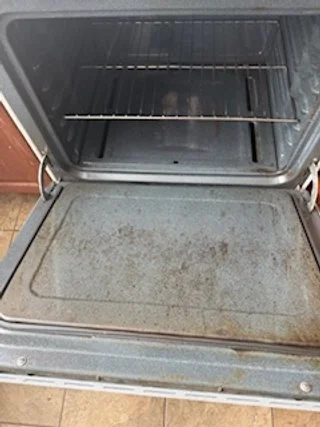 Empty oven with a dirty baking surface and grill rack