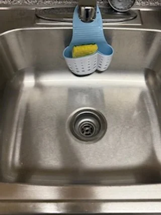 A kitchen sink with a blue and white dish scrubber hanging above it.