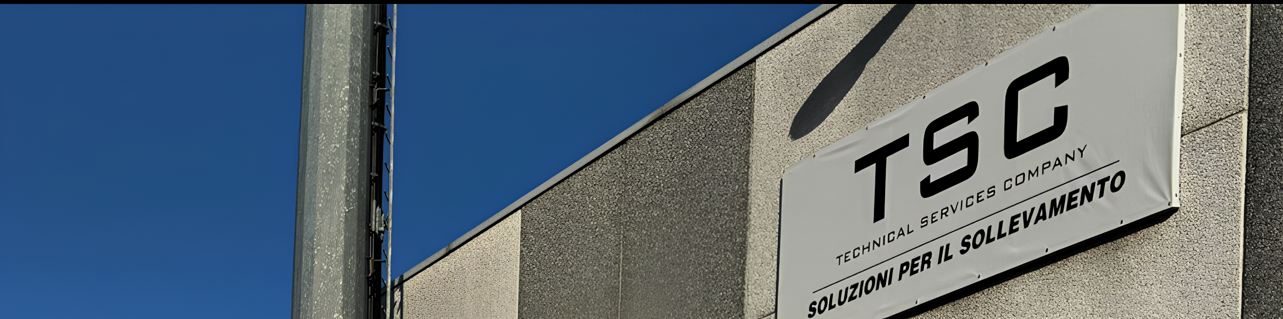 Segnale con il logo e il nome TSIC, azienda di servizi tecnici, sulla parete di un edificio con cielo azzurro sullo sfondo.