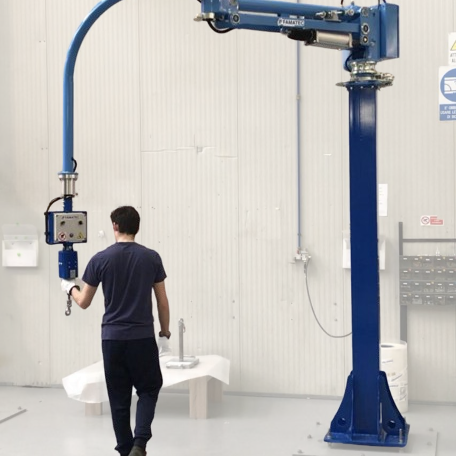 Persona che utilizza un braccio robotico blu in un ambiente industriale, con un tavolo e dispositivi di sicurezza sul muro