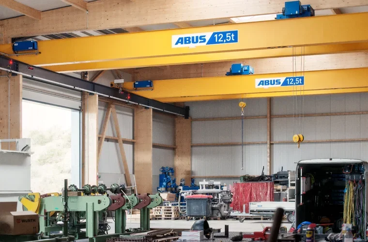 Interno di un'officina con un carroponte marca ABUS, capacità di 12,5 tonnellate, e vari attrezzi e veicoli.