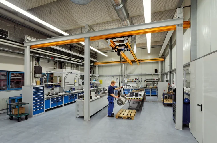 Un ragazzo in un laboratorio di fianco a un impianto sospeso di sollevamento, portata 1000 kg