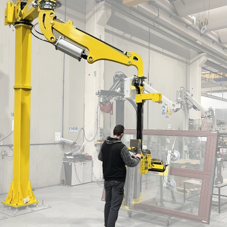 Operaio in fabbrica che utilizza un robot industriale giallo per movimentare una grande finestra in vetro.