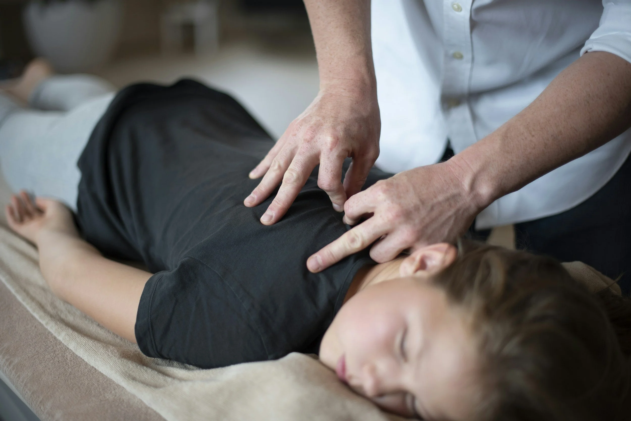 Person receiving chiropractic or physical therapy treatment while lying on a treatment table.