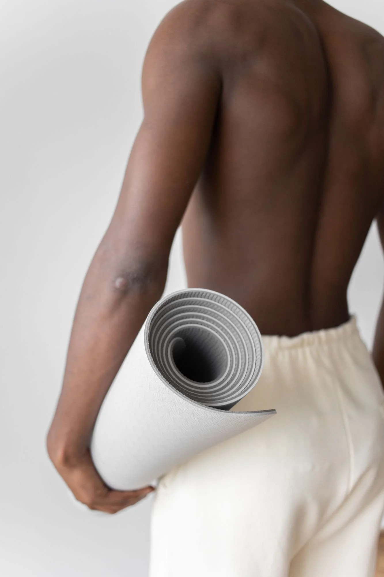A person holding a rolled yoga mat.